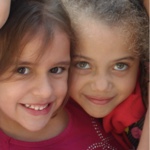 Rosto de duas meninas com camiseta vermelha da Fundação Julita