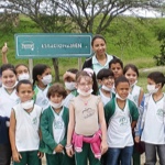 Doze crianças do Projeto Verdescola em pé com camiseta branca posando para foto junto com sua professora