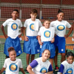 Sete crianças da Fundação Tênis com uniforme branco posando para foto